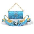 Blue glittery shoes with gold accents and a matching handbag on a white background, Obroi