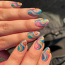 Nails with colorful swirled design held by a person, Obroi