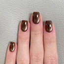 Hand with brown nail polish on a light gray background, Obroi
