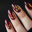Maroon nails with gold leaf designs on a black background, Obroi