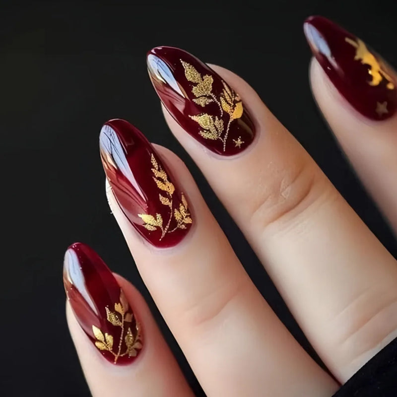 Maroon nails with gold leaf designs on a black background, Obroi