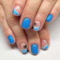 Nails with blue polish and beach-themed designs on a white background, Obroi