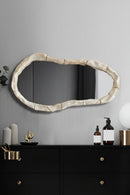 Decorative mirror with a textured frame on a wall above a shelf, Obroi