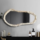 Decorative mirror with a textured frame on a wall above a shelf, Obroi