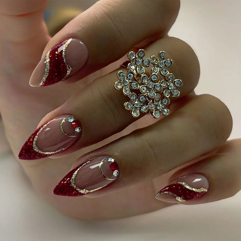 Hand with red and gold nail art holding a decorative ring, Obroi