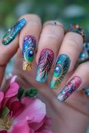Nails with peacock feather design and glittery finish, held against a blurred floral background, Obroi