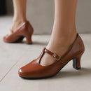 Obroi Brown high-heeled shoes with a strap worn by a person on a light floor.
