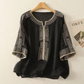 Black blouse with white embroidery on a hanger against a light background, Obroi