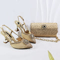 A matching women's evening set featuring a pair of pointed-toe slingback high heels and a matching clutch bag, both in a metallic champagne gold color with rhinestone embellishments. The shoes have chunky kitten heels and crystal-embellished toe caps, while the clutch has a rhinestone-covered body and a gold chain strap, Obroi