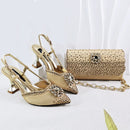 A matching women's evening set featuring a pair of pointed-toe slingback high heels and a matching clutch bag, both in a metallic champagne gold color with rhinestone embellishments. The shoes have chunky kitten heels and crystal-embellished toe caps, while the clutch has a rhinestone-covered body and a gold chain strap, Obroi