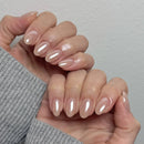 Close-up of a hand with beige nail polish on a neutral background, Obroi