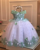 Green and white dress with floral details on a stand against a neutral background