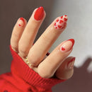 Obroi Hand with red nail polish and heart designs, wearing a red sweater.