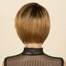 Back view of a person wearing a short, straight bob wig with dark roots and warm blonde highlights, against a light beige background. The Obroi logo is visible in the top left corner.