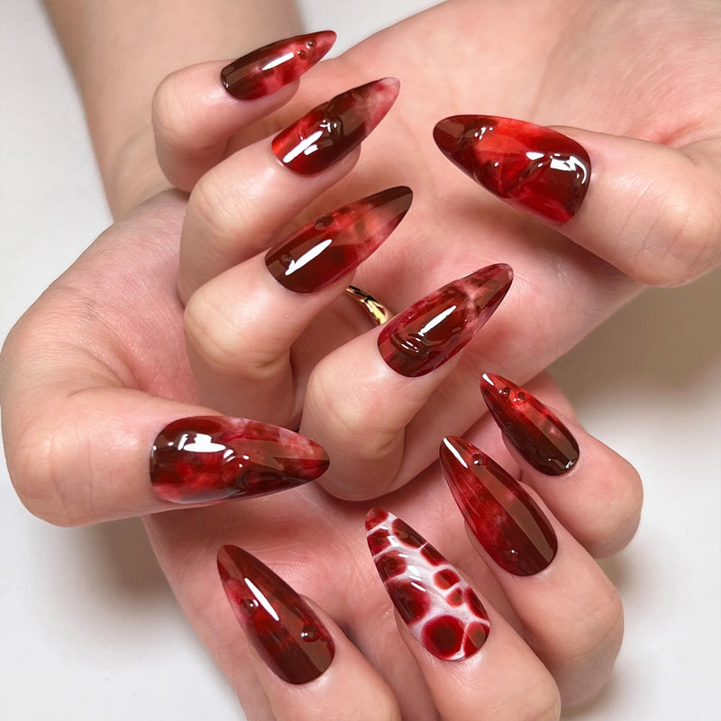 Obroi Close-up of a hand with red and brown marbled nail art on a white background