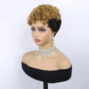 A short curly wig with a golden-brown and black ombre look, styled on a mannequin bust wearing a black off-the-shoulder top and a rhinestone choker against a plain light background, Obroi