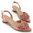 Pair of pink high-heeled shoes with floral embellishments on a white background, Obroi
