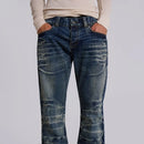 Person wearing distressed blue jeans on a plain background, Obroi