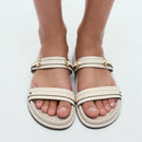 Beige sandals with gold accents worn by a person on a white background, Obroi