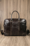 Brown leather briefcase with shoulder strap on a wooden surface, Obroi