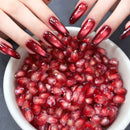 Bowl of pomegranate seeds with hands with red nail polish holding them, Obroi