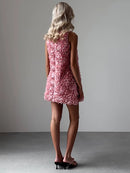Woman wearing a pink floral dress against a plain background, Obroi