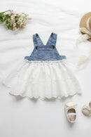 Denim pinafore dress with white lace skirt on a light surface, accompanied by a straw hat and baby shoes, Obroi