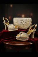 Pair of ornate high-heeled shoes with matching handbag on a dark background, Obroi