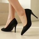 Black high-heeled shoes worn by a person on a neutral background, Obroi