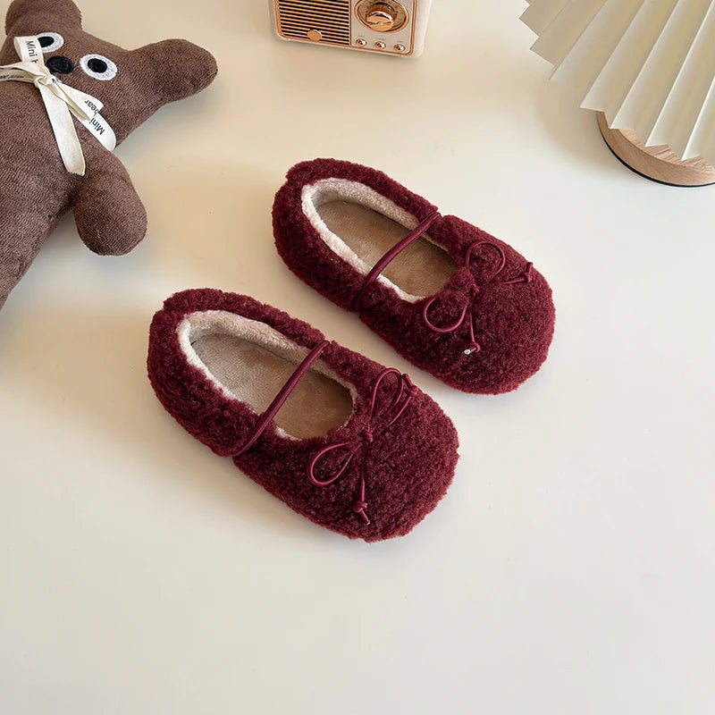 Pair of maroon slippers with a teddy bear toy on a light surface, Obroi