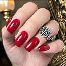 Hand with red nails wearing a decorative ring against a blurred background, Obroi