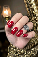 Hand with red nails wearing a decorative ring against a blurred background, Obroi