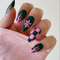 Nails with green and pink designs on a light pink fabric background, Obroi