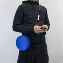Person wearing a black jacket with a blue round bag on a white background, Obroi