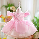 Pink children's dress on a mannequin with a blurred floral background, Obroi