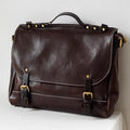 Brown leather bag with gold buckles on a white surface, Obroi