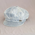 Light blue denim cap with a brand logo on a beige background, Obroi