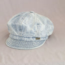 Light blue denim cap with a brand logo on a beige background, Obroi