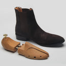 Dark brown leather boot and wooden shoe tree on a light gray background with 'Obroi' branding.