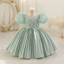 Light green dress with puffed sleeves on a mannequin against a decorative background, Obroi
