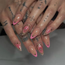 Obroi Close-up of a hand with pink and gold nail art on a neutral background