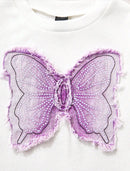 A close-up of a white crewneck sweatshirt featuring a large, decorative lavender butterfly applique on the front. The butterfly is made of sheer lavender mesh with black embroidered outlines, white bead details, and a frayed, raw-edge finish, Obroi