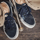 Navy blue sneakers with white soles on a wooden floor, Obroi