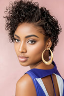 Woman with styled hair wearing a blue top against a pink background, Obroi