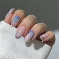 Hand with pink and holographic nails against a neutral background, Obroi