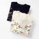 Two folded sweaters with floral patterns on a white background