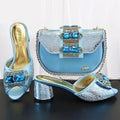 Blue high-heeled shoes and matching handbag with decorative elements on a dark surface, Obroi