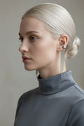 Woman wearing silver fringe earrings with gold and silver earrings displayed on a stone surface, Obroi