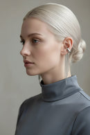 Woman wearing silver fringe earrings with gold and silver earrings displayed on a stone surface, Obroi