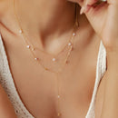 Gold necklace with small stones worn by a person, close-up on skin